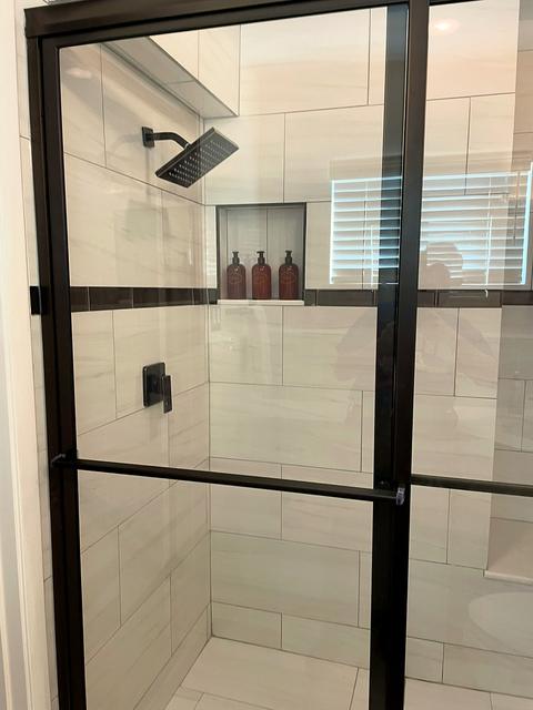 Glass shower with black fixtures and a long niche