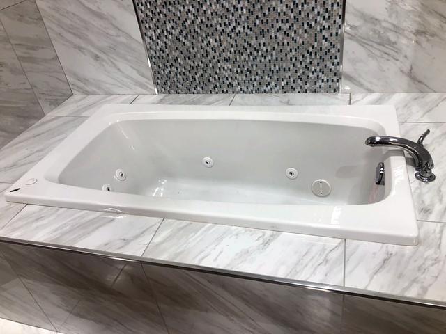 Jetted tub with marble tile and mosaic in Fort Worth